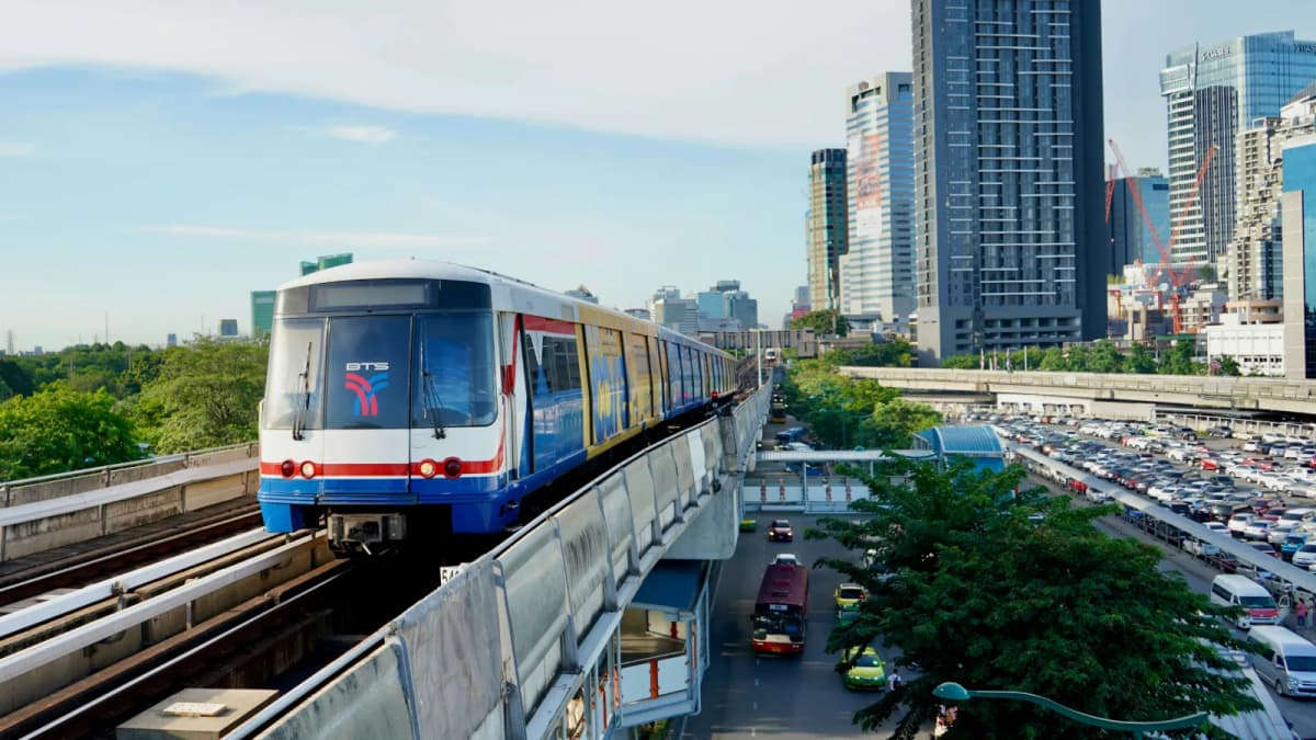 BTS Skytrain running on an elevated track through central Bangkok traffic and towers