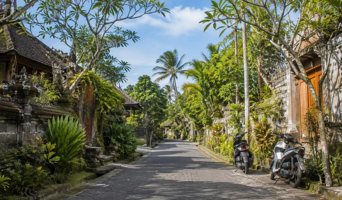 A peaceful Bali village street with parked scooters and tropical greenery