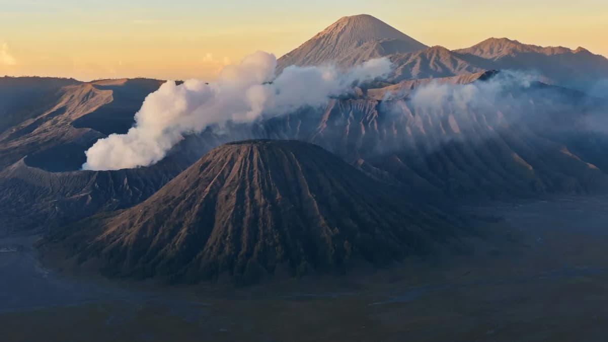 Mount Bromo crater steaming at sunrise with Mount Batok in front and Semeru behind in East Java
