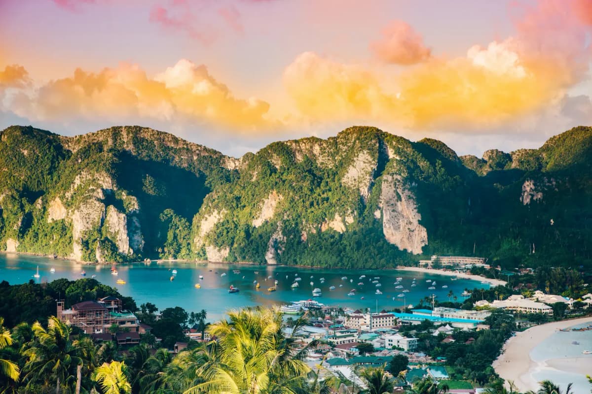 Boats in the bay of Phi Phi Island below green limestone hills at sunset