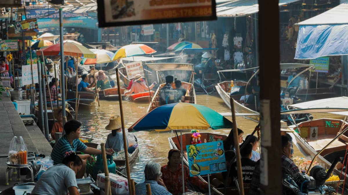 Vendor boats under colourful umbrellas crowding a canal at a floating market in Thailand