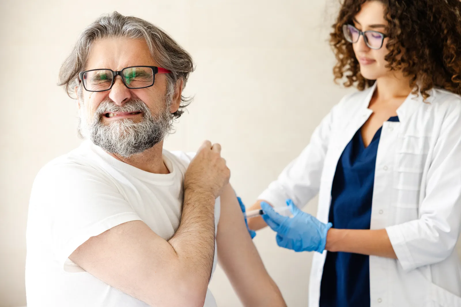 Health worker giving an adult man a vaccine injection in the upper arm at a clinic