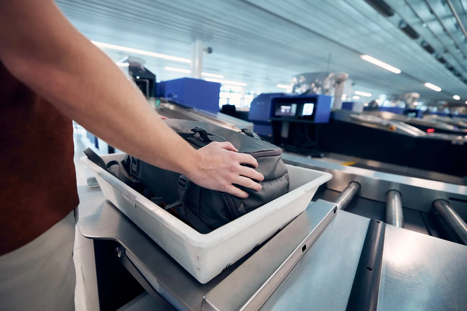 Passenger placing a bag into a tray before it goes through an airport X-ray scanner