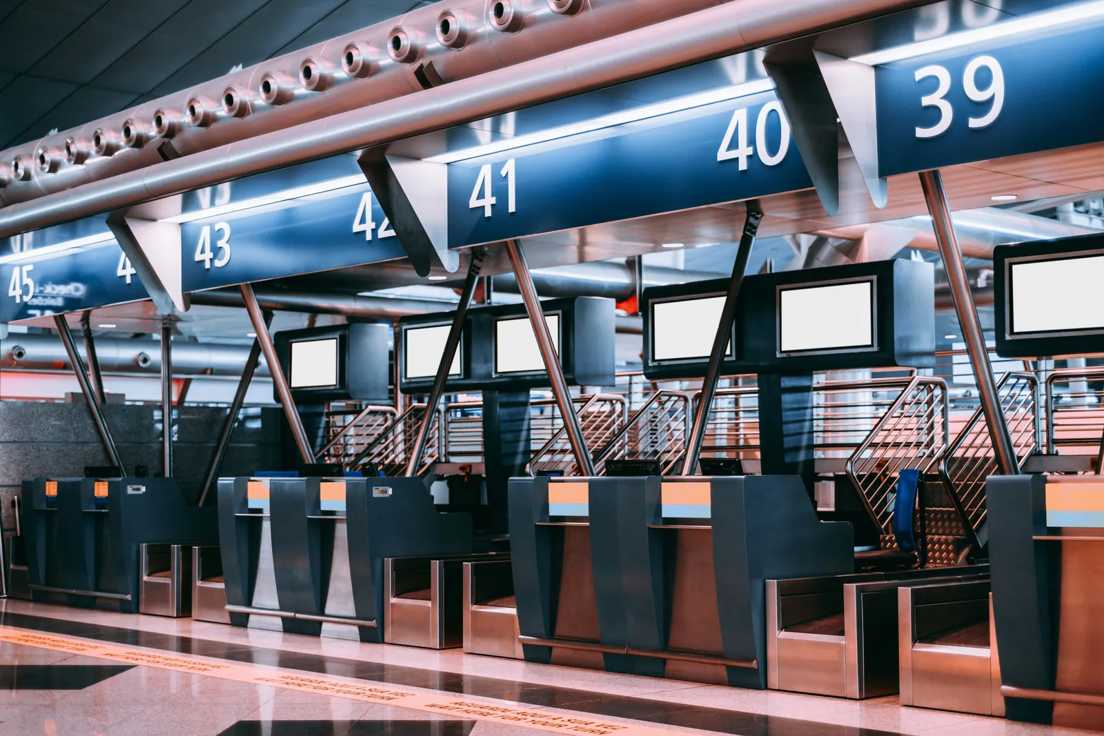 Row of numbered check-in counters in a modern airport departure hall before opening