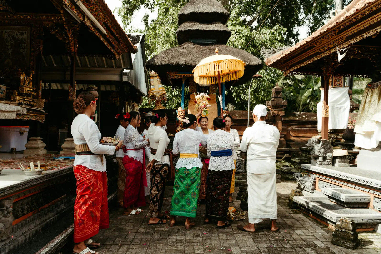 Balinese worshippers in white temple clothes and sarongs carrying offerings at a ceremony