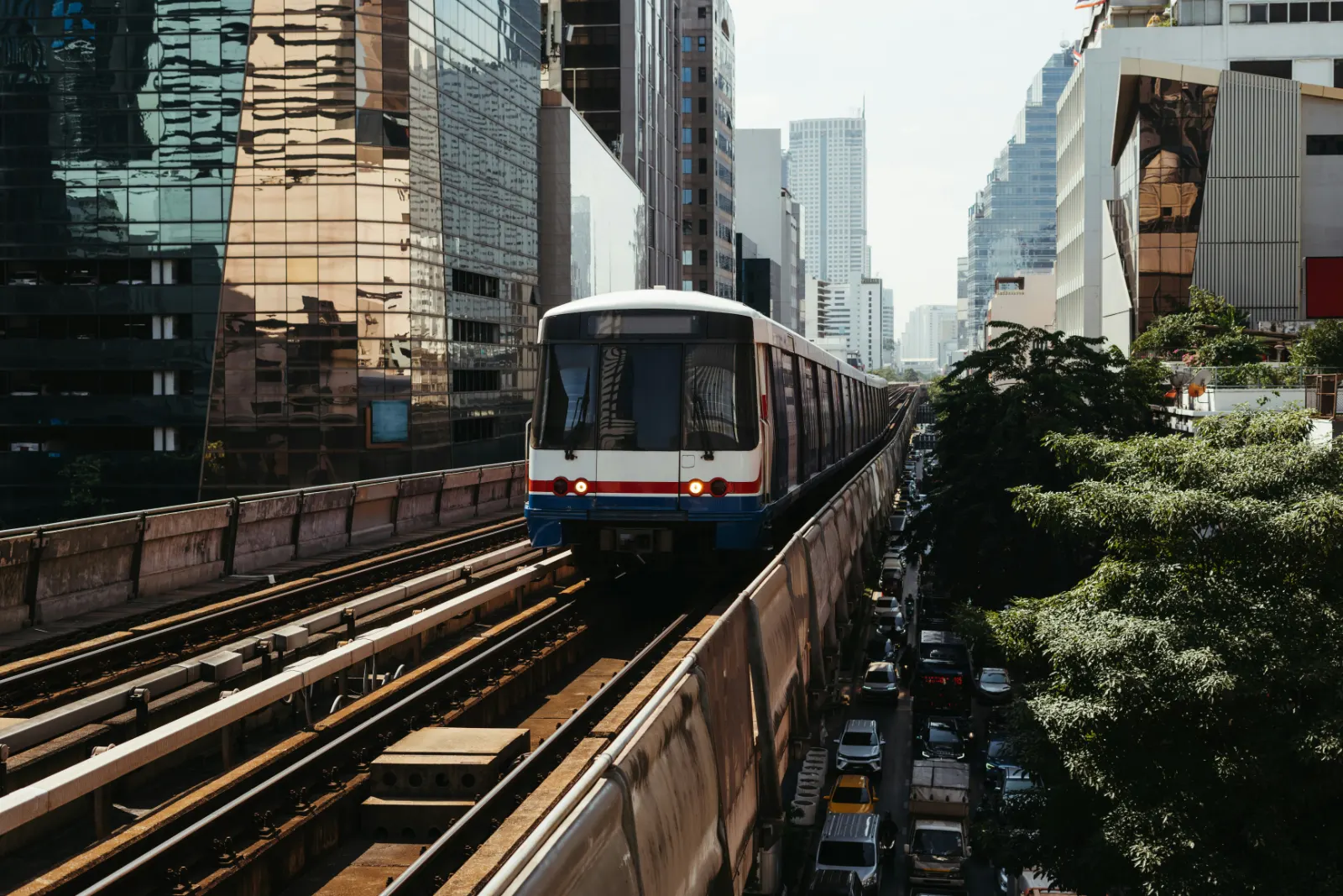 BTS Skytrain on its elevated track above a Bangkok street lined with towers