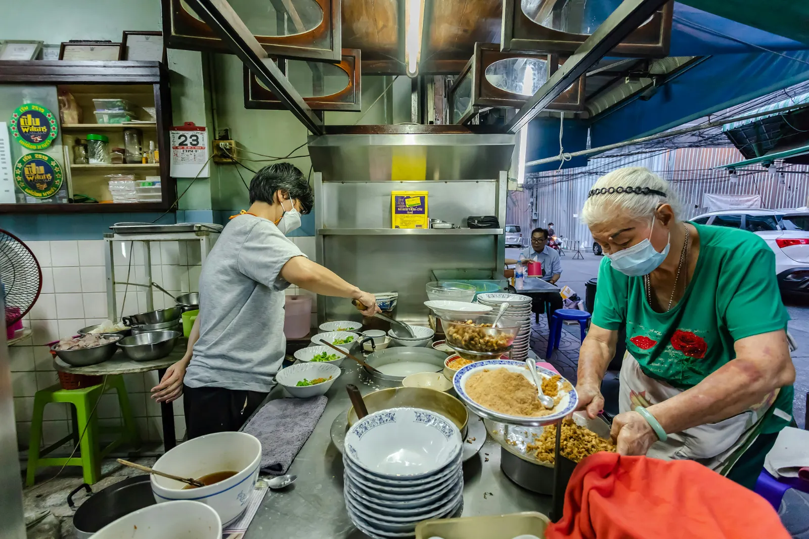 Street food cooks preparing dishes at a busy roadside stall in Bangkok