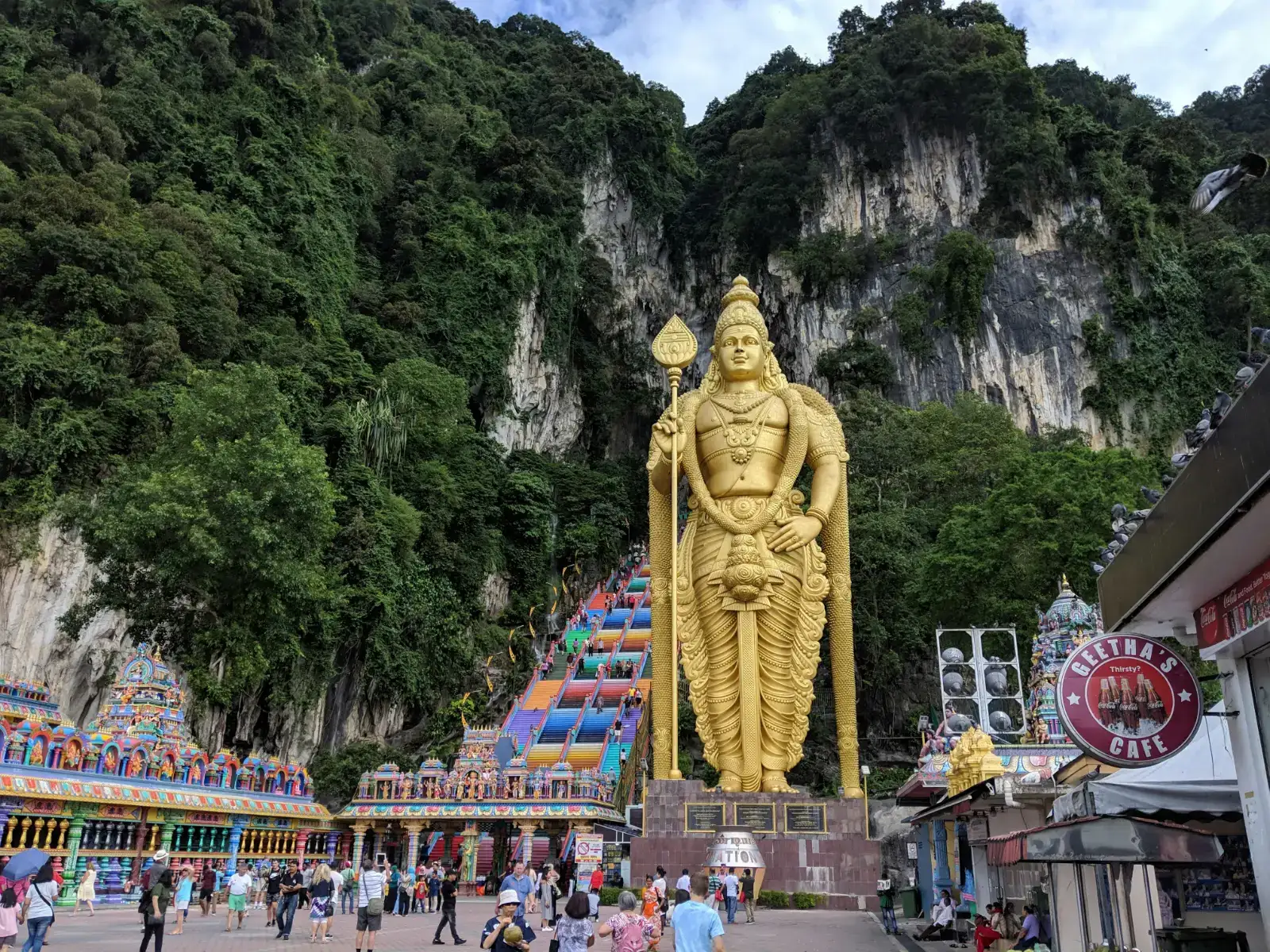 Lord Murugan statue at the foot of the Batu Caves limestone hill with visitors below