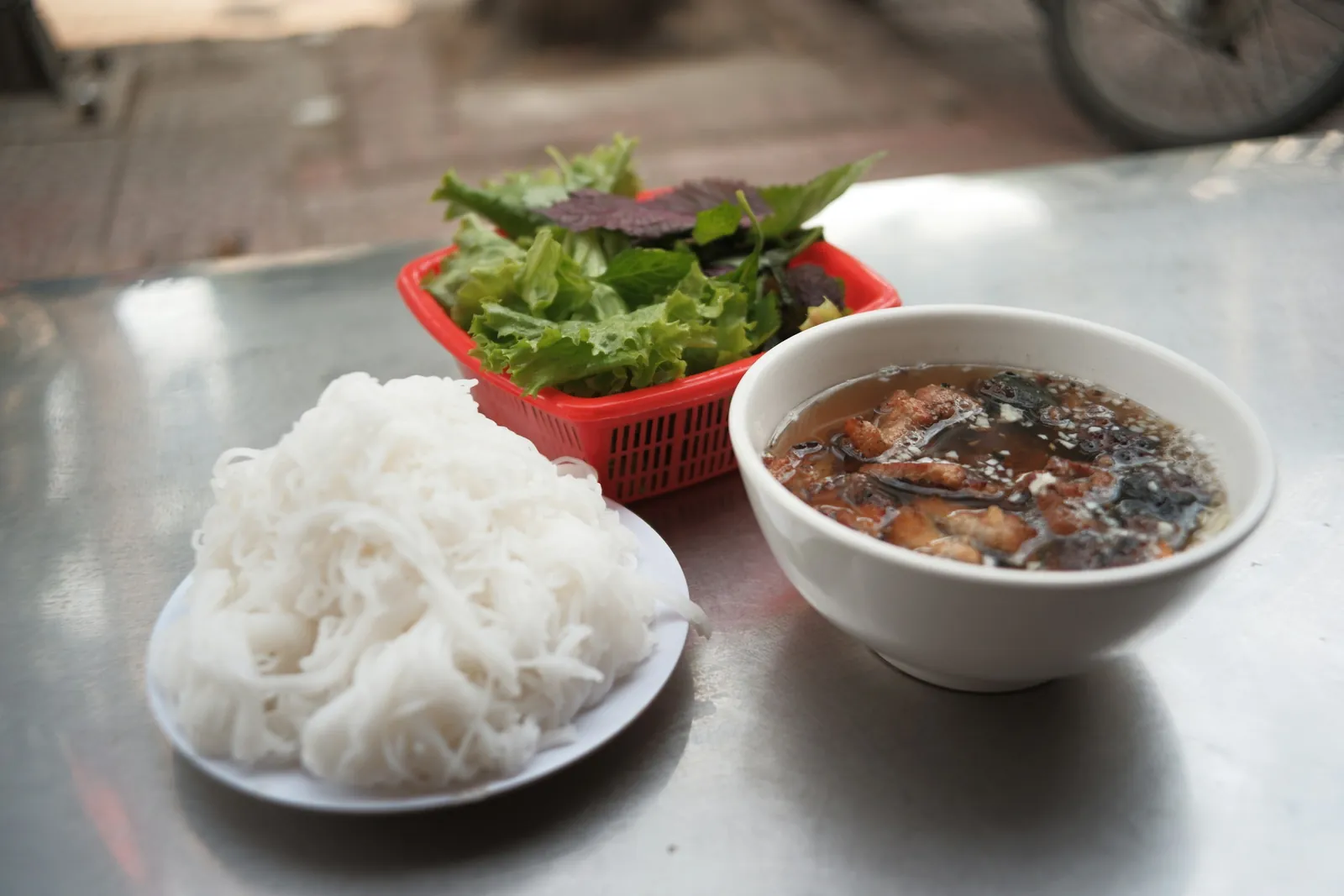 Bun cha served with rice noodles, fresh herbs and a bowl of dipping broth with pork