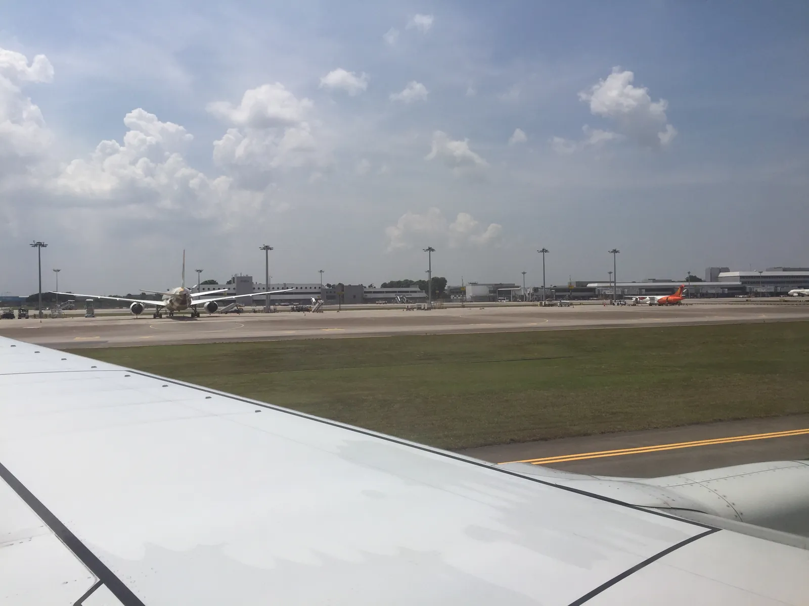 View over an aircraft wing of the runway and terminals at Singapore Changi Airport
