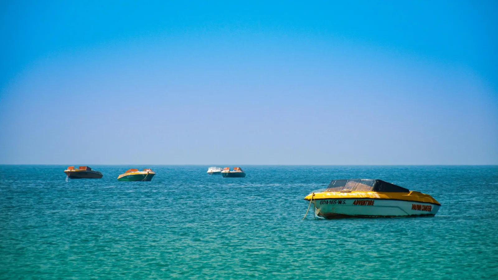 Small boats floating on calm turquoise water off Colva Beach in South Goa