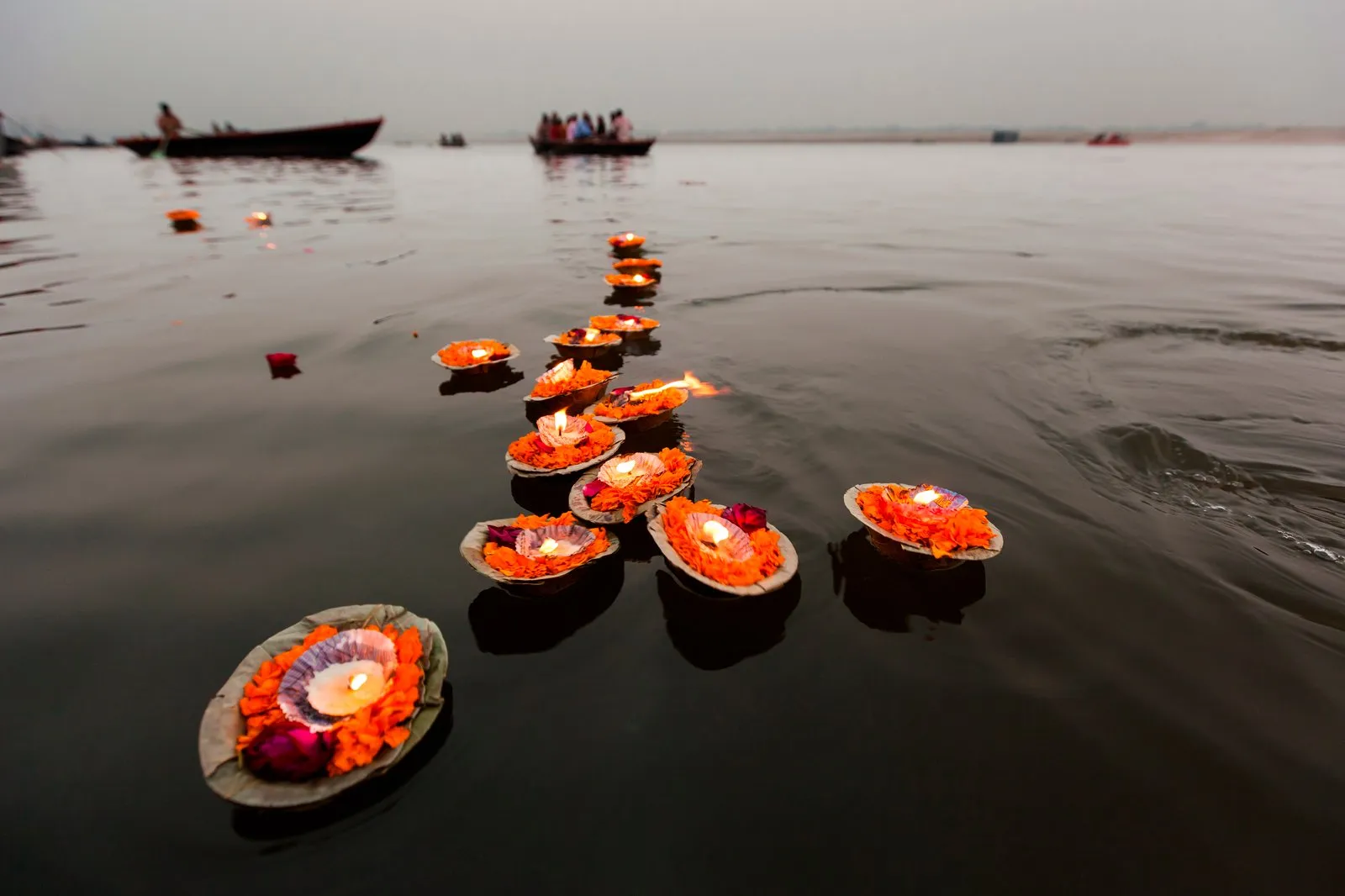 Small leaf lamps with marigold petals and lit flames floating on the Ganges River in Varanasi