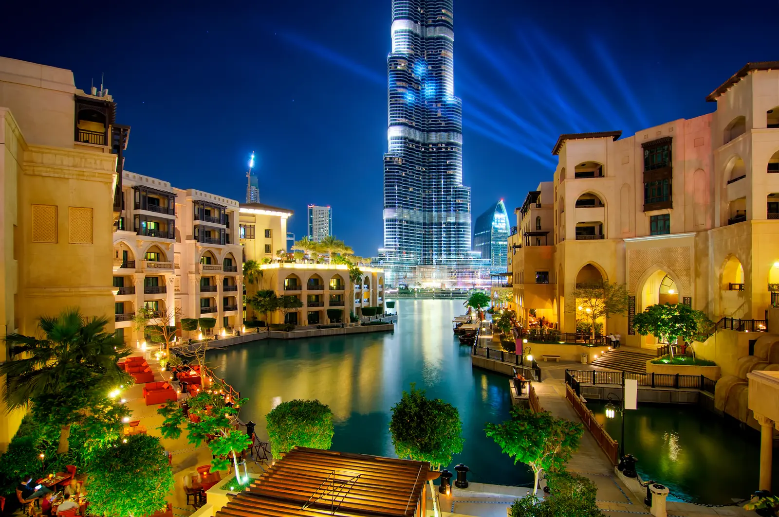Downtown Dubai at night with palm trees, low rise buildings and the Burj Khalifa behind