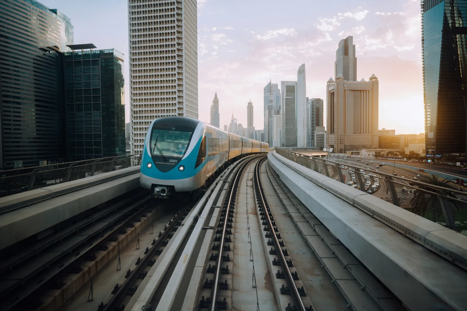 Dubai Metro train running on the elevated track between city towers in daylight
