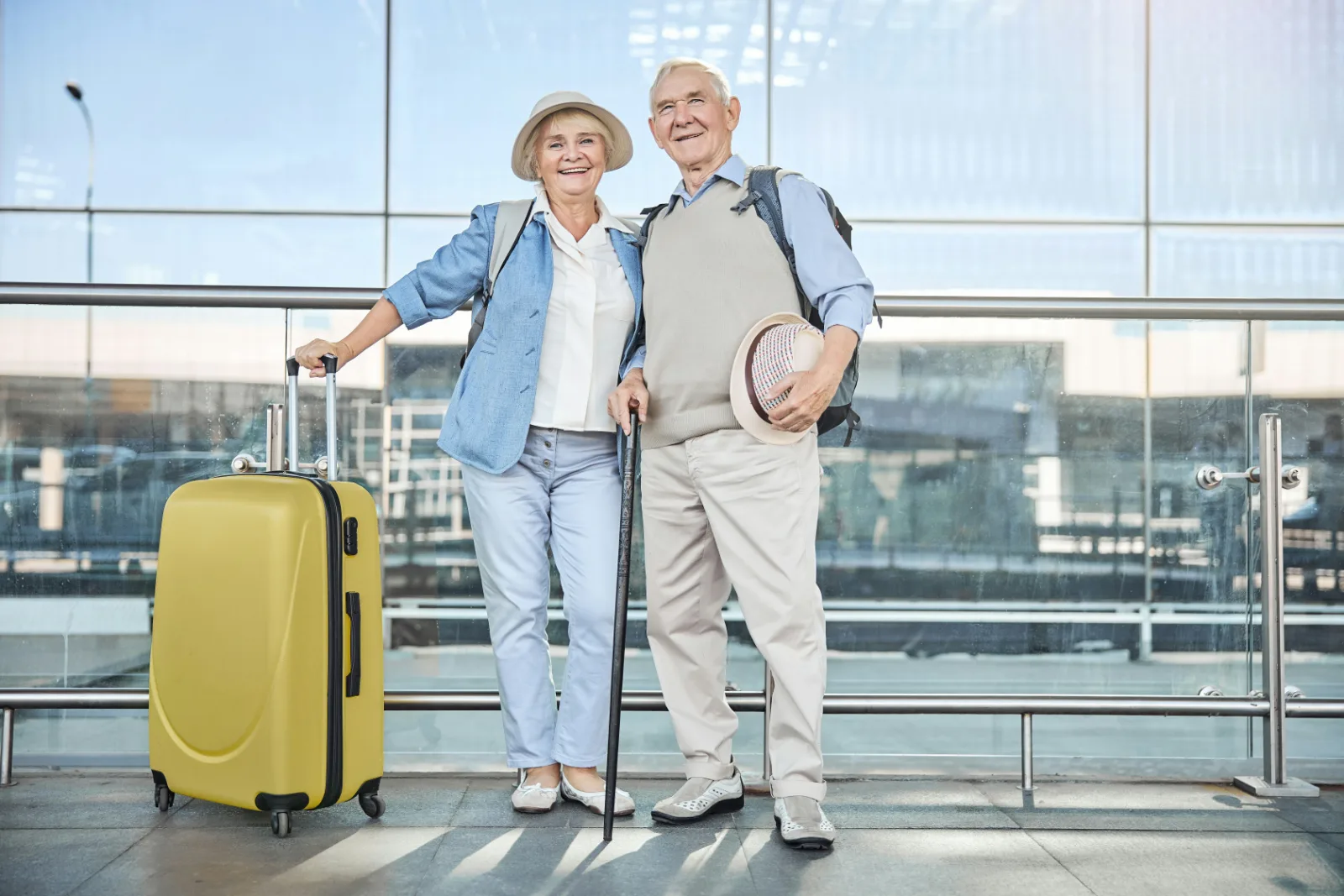Elderly couple walking through an airport terminal with their suitcases before a flight