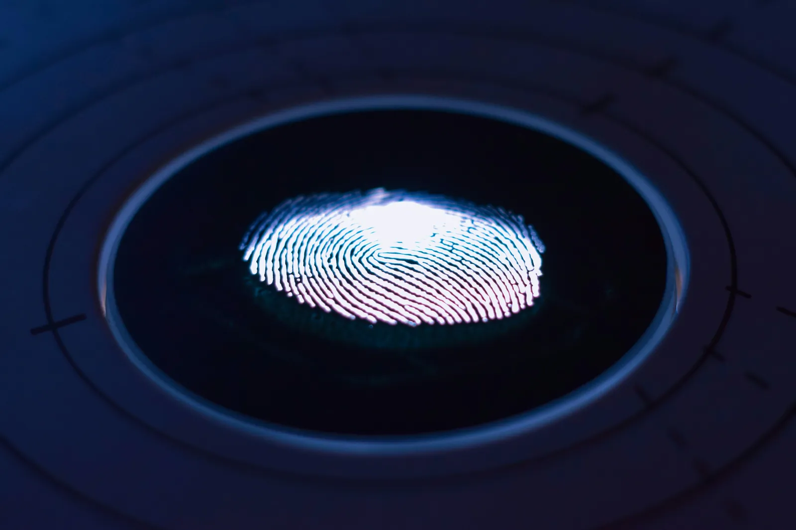 Glowing fingerprint on a dark biometric scanner, like those used for passport fingerprints