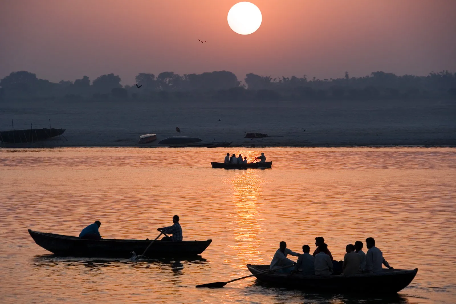 Rowing boats with passengers silhouetted on the Ganges as the sun rises over Varanasi
