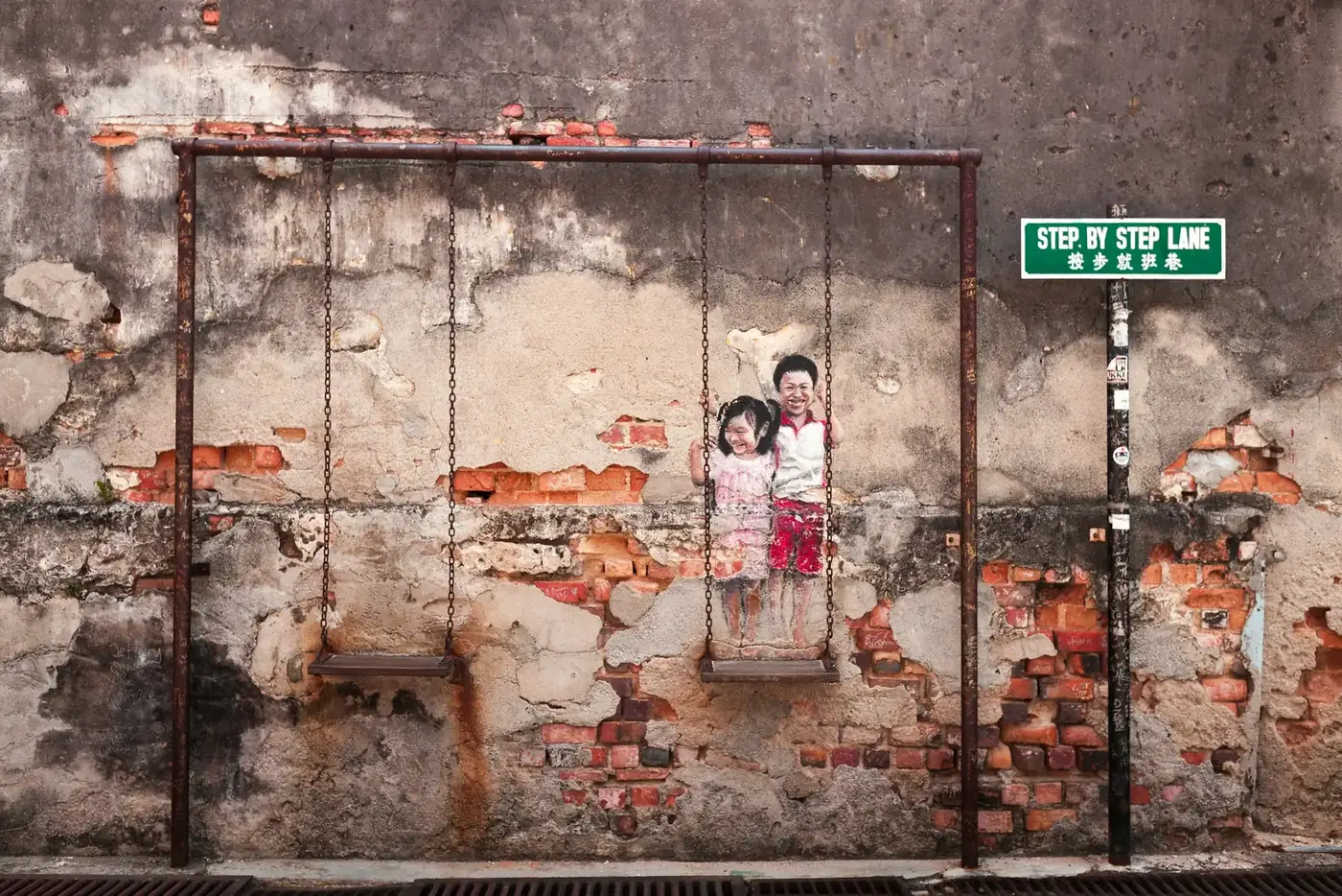 Famous Kids on a Swing street art mural on an old wall in George Town, Penang