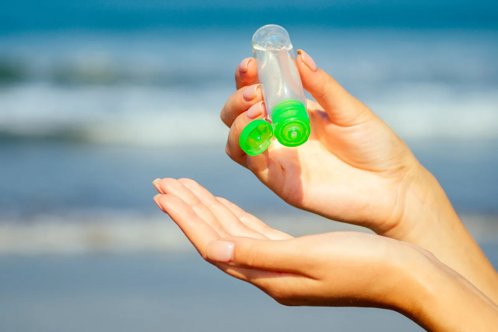 Traveller squeezing hand sanitizer into their palm on a sunny beach