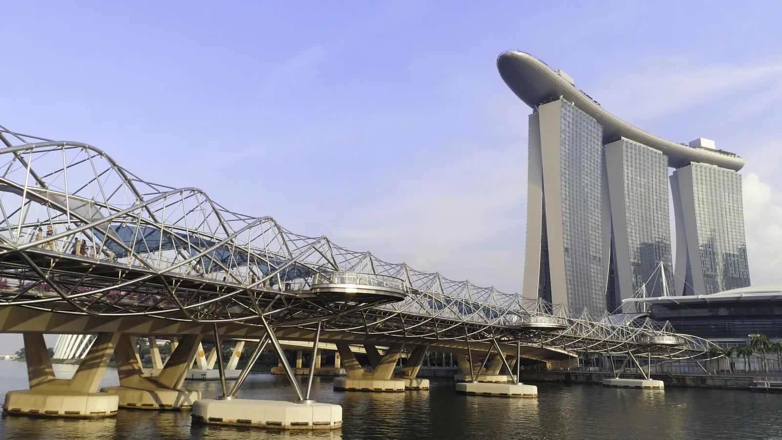 Helix Bridge walkway curving toward the three towers of Marina Bay Sands in Singapore