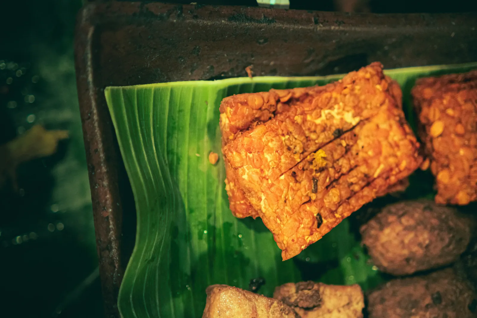 Fried tempeh slices served on a banana leaf, a common Indonesian vegetarian protein