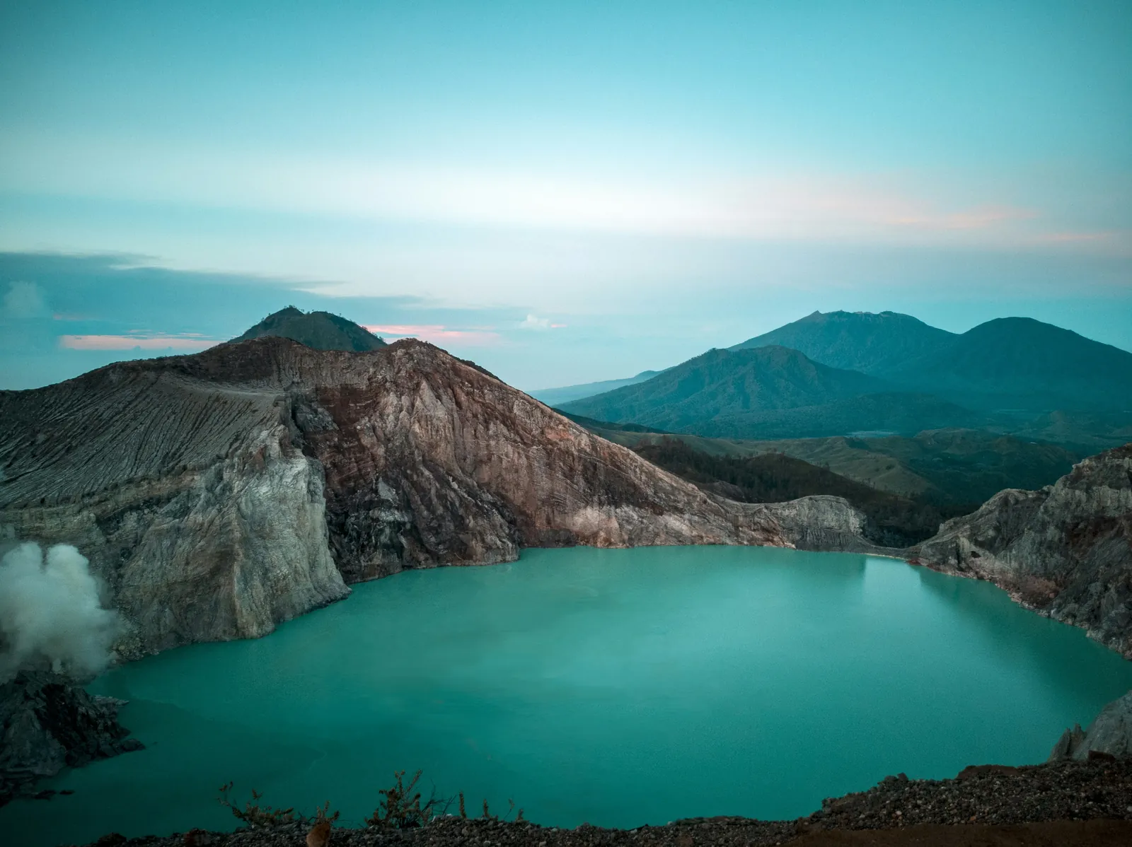 Turquoise acid lake inside the Kawah Ijen crater in East Java under a pale sky