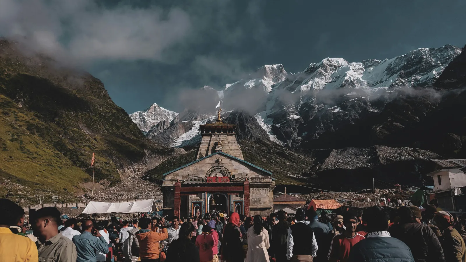 Pilgrims gathered before Kedarnath Temple with snow capped Himalayan peaks behind in Uttarakhand