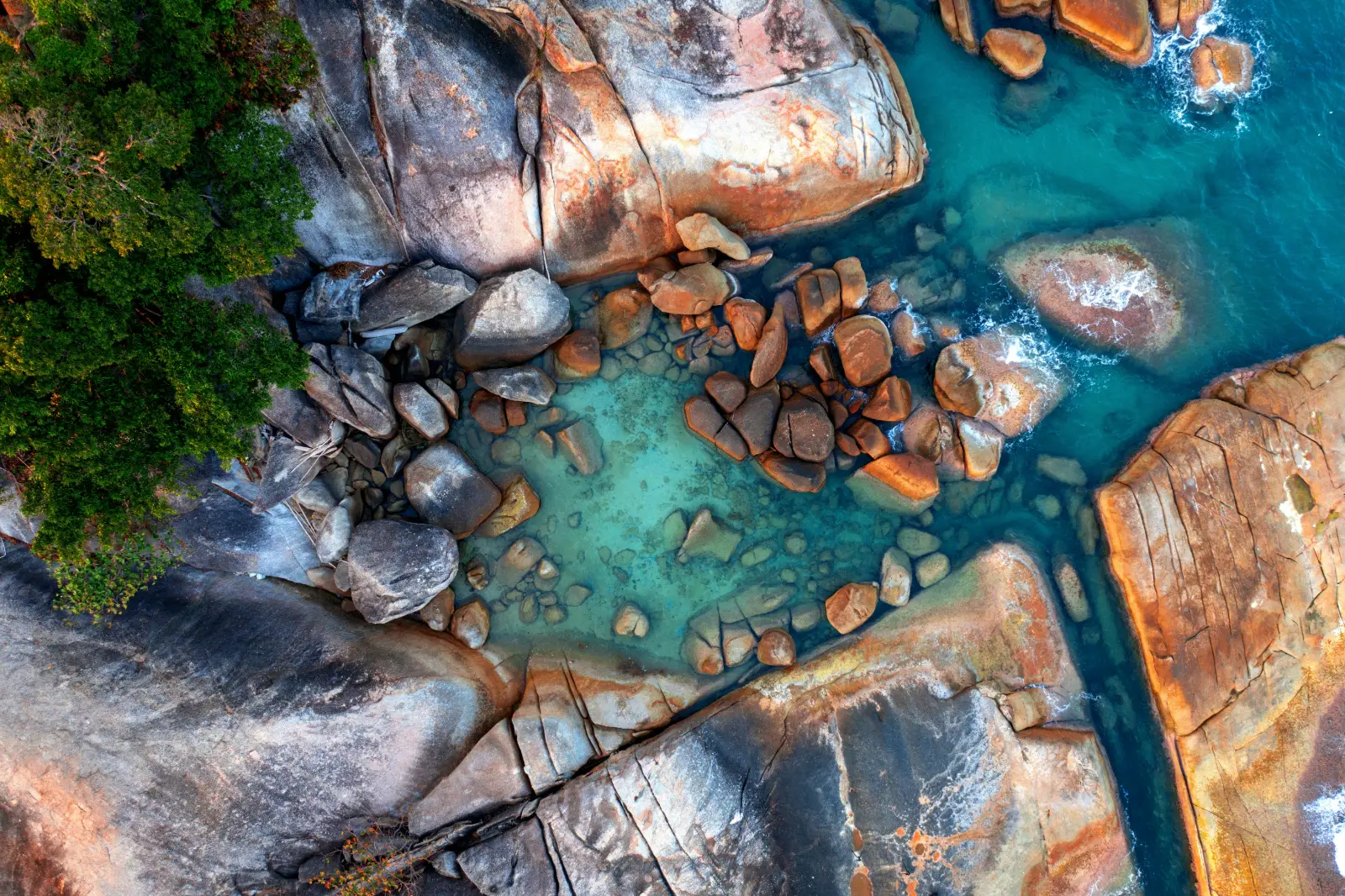 Aerial view of the rocky shoreline and clear water near Lamai Beach on Koh Samui