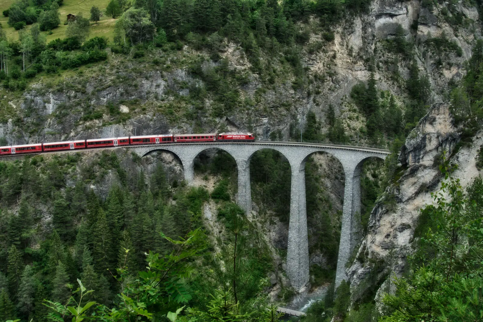 Red train crossing the stone Landwasser Viaduct near Filisur in the Swiss Alps