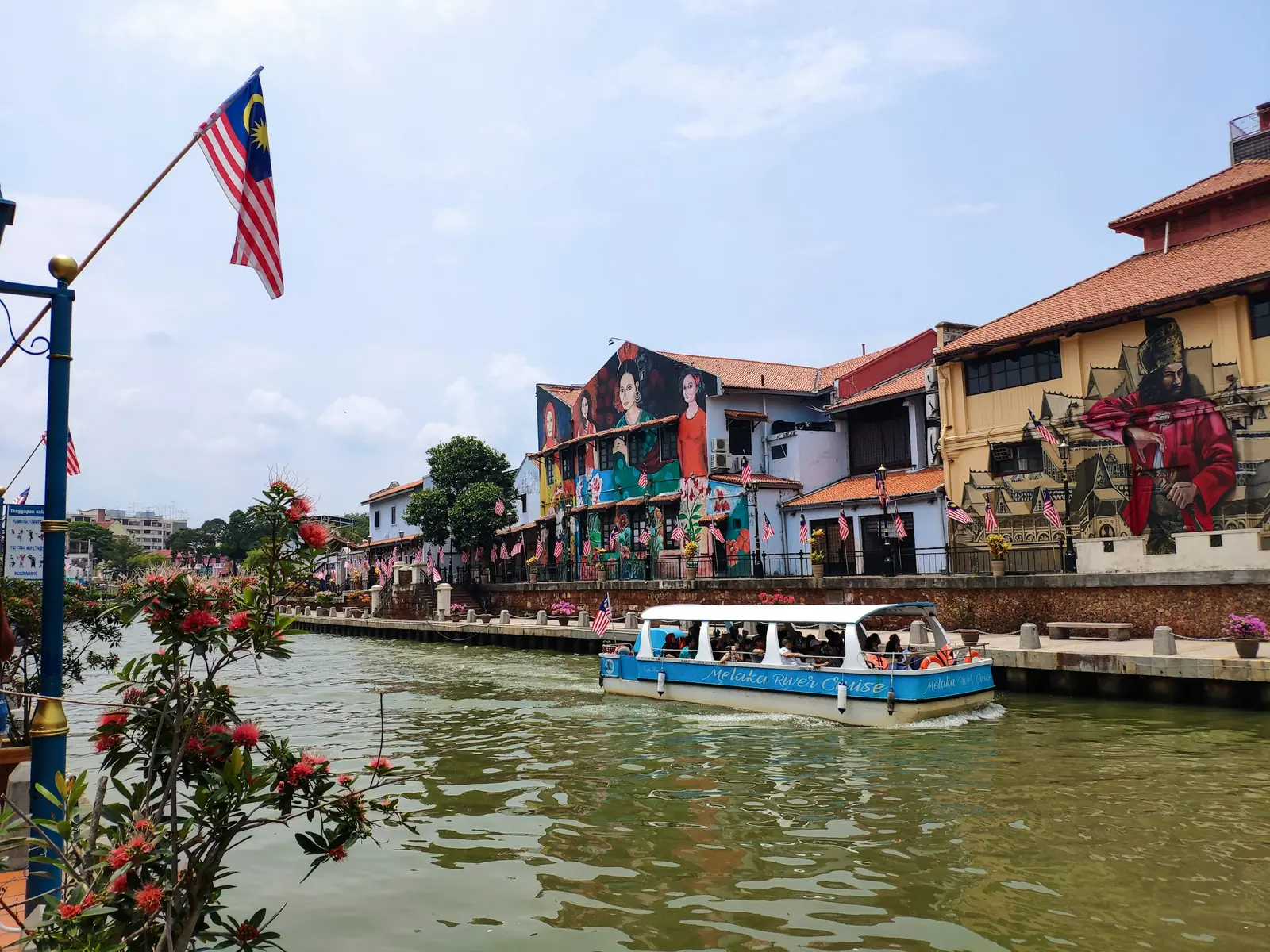 River cruise boat passing colourful heritage houses on the Malacca River in Melaka
