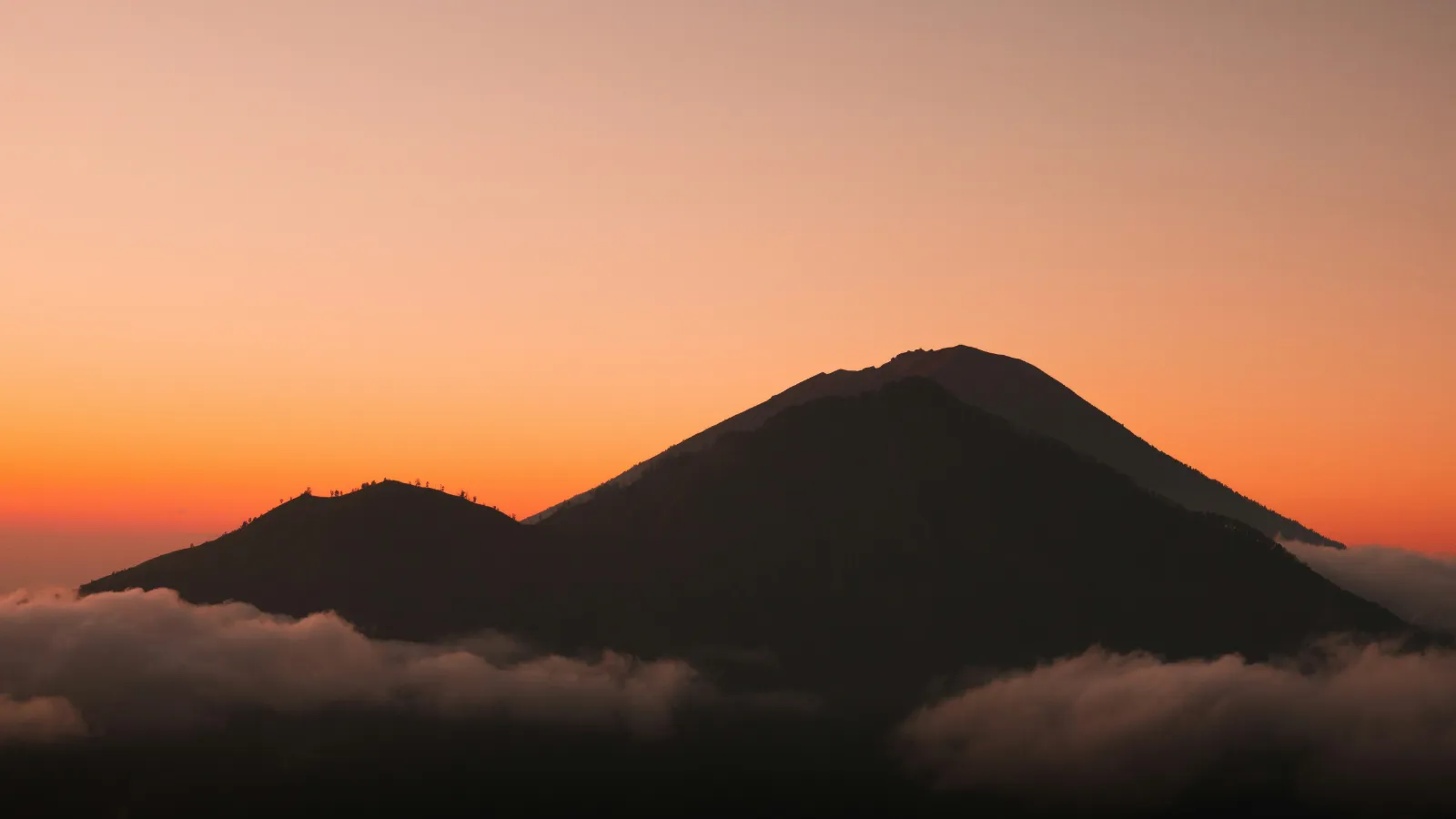Mount Agung volcano silhouetted against an orange sunset sky in eastern Bali