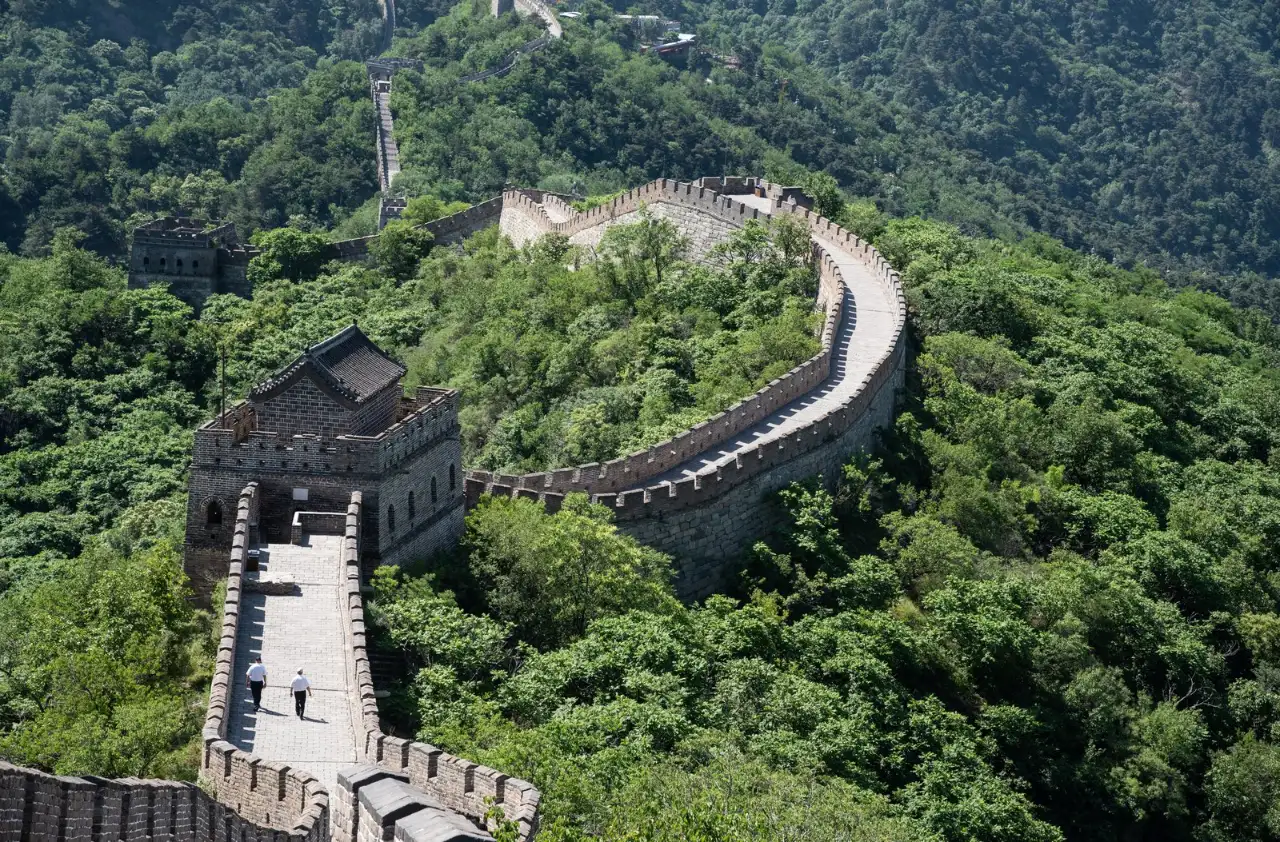 Mutianyu section of the Great Wall winding past a watchtower through green forested hills