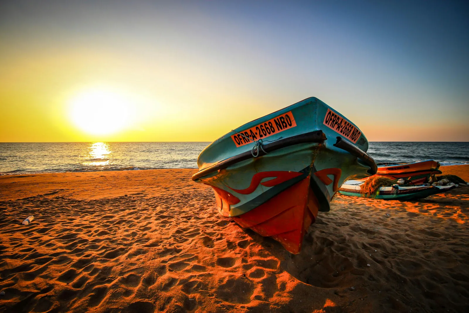 Colourful fishing boat resting on Negombo beach at sunset on the west coast of Sri Lanka