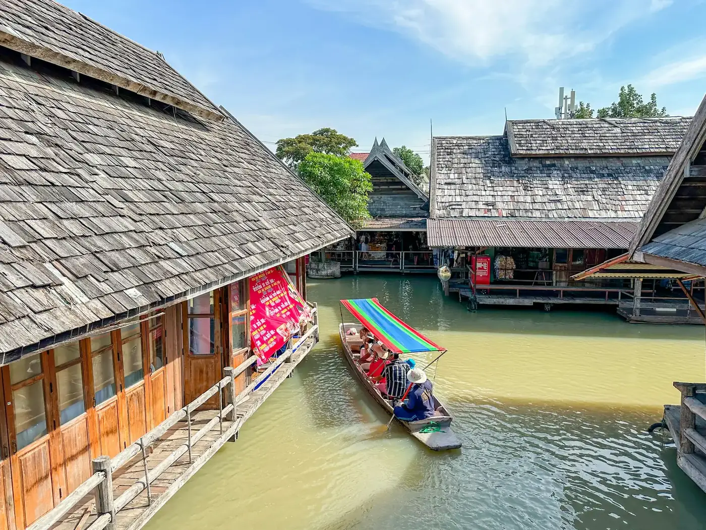 Wooden stalls and a long tail boat on the canal at Pattaya Floating Market