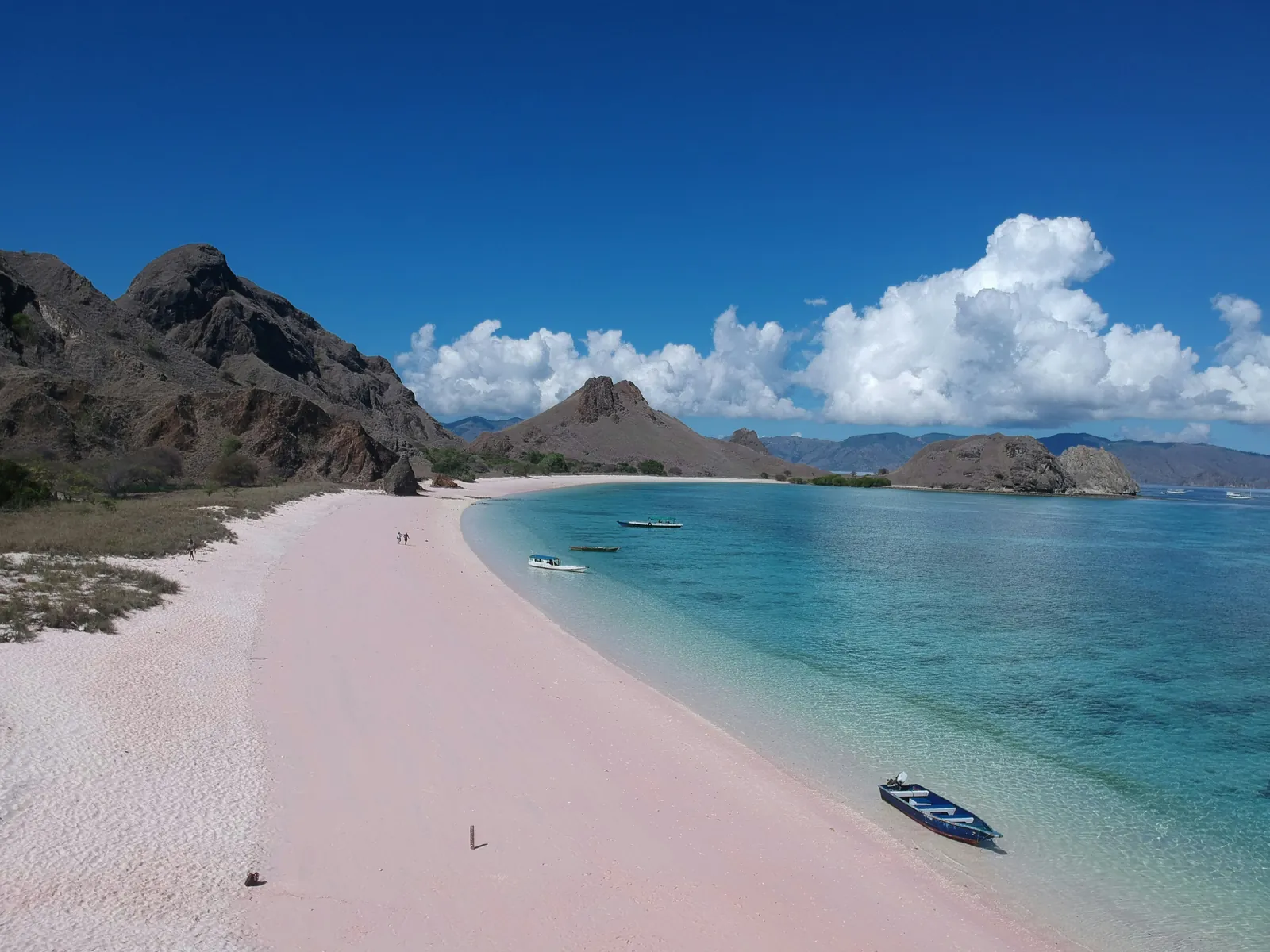 Pink sand shoreline and turquoise water at Pink Beach in Komodo National Park with a small boat