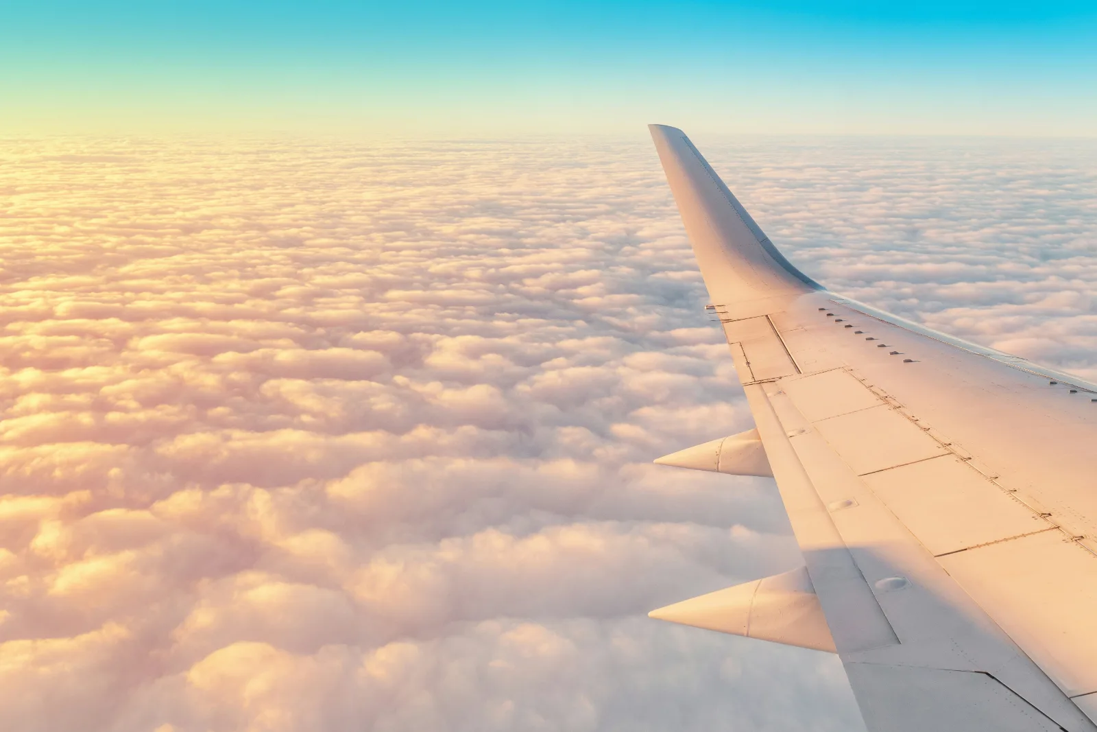 Plane wing over golden clouds at sunrise on a long haul flight towards Europe
