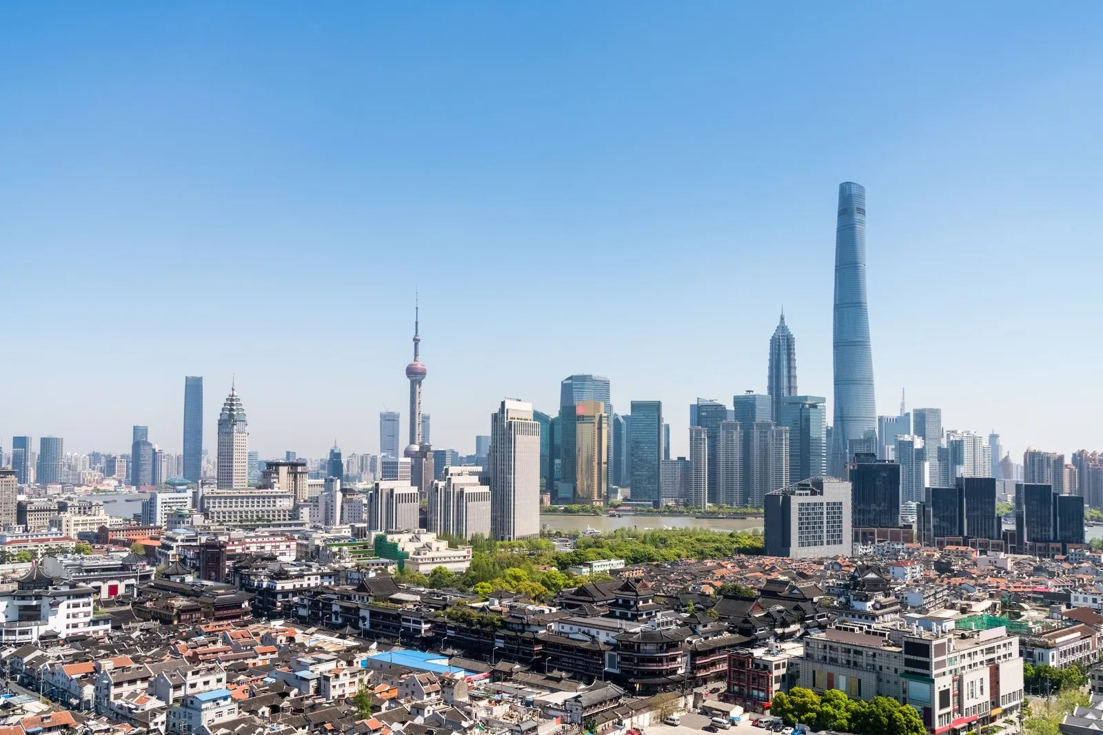 Shanghai Tower rising above the Lujiazui skyline and old town rooftops on a clear day