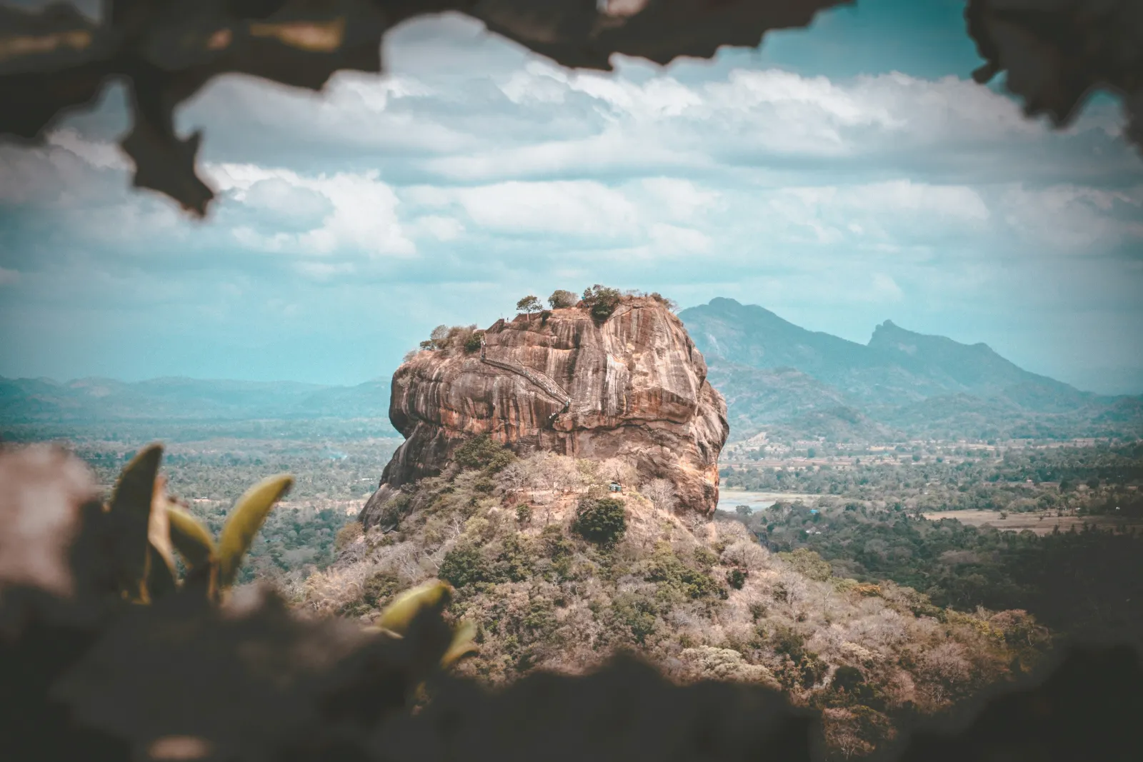 Sigiriya Lion Rock standing above green jungle with distant hills in central Sri Lanka