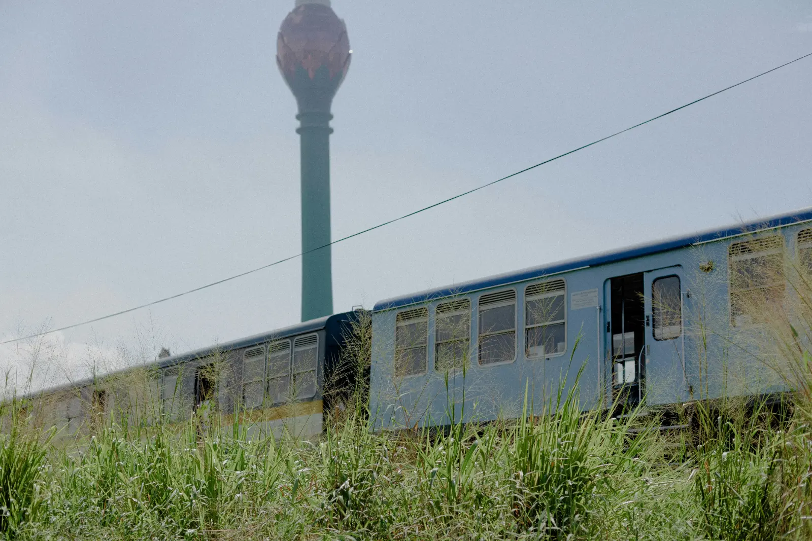 Blue Sri Lankan passenger train passing in front of the Lotus Tower in Colombo