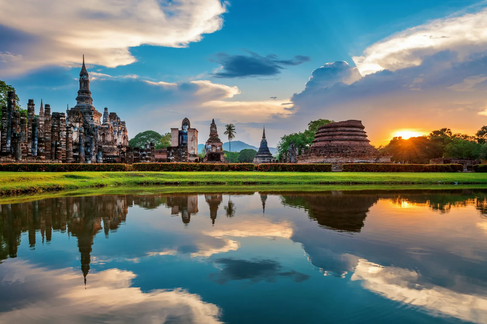 Seated Buddha statue among the Wat Mahathat ruins in Sukhothai Historical Park, Thailand