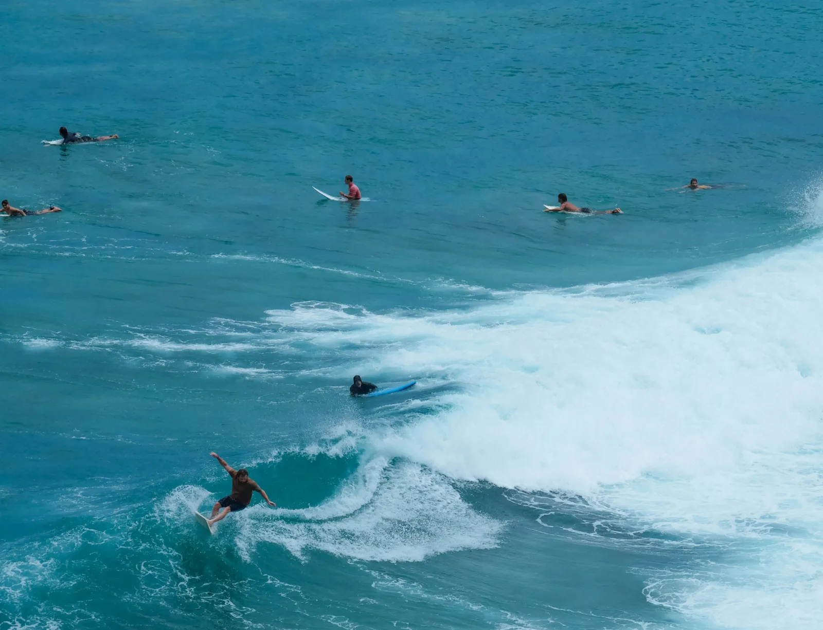 Surfers waiting in strong waves off Uluwatu Beach on the Bukit Peninsula, Bali