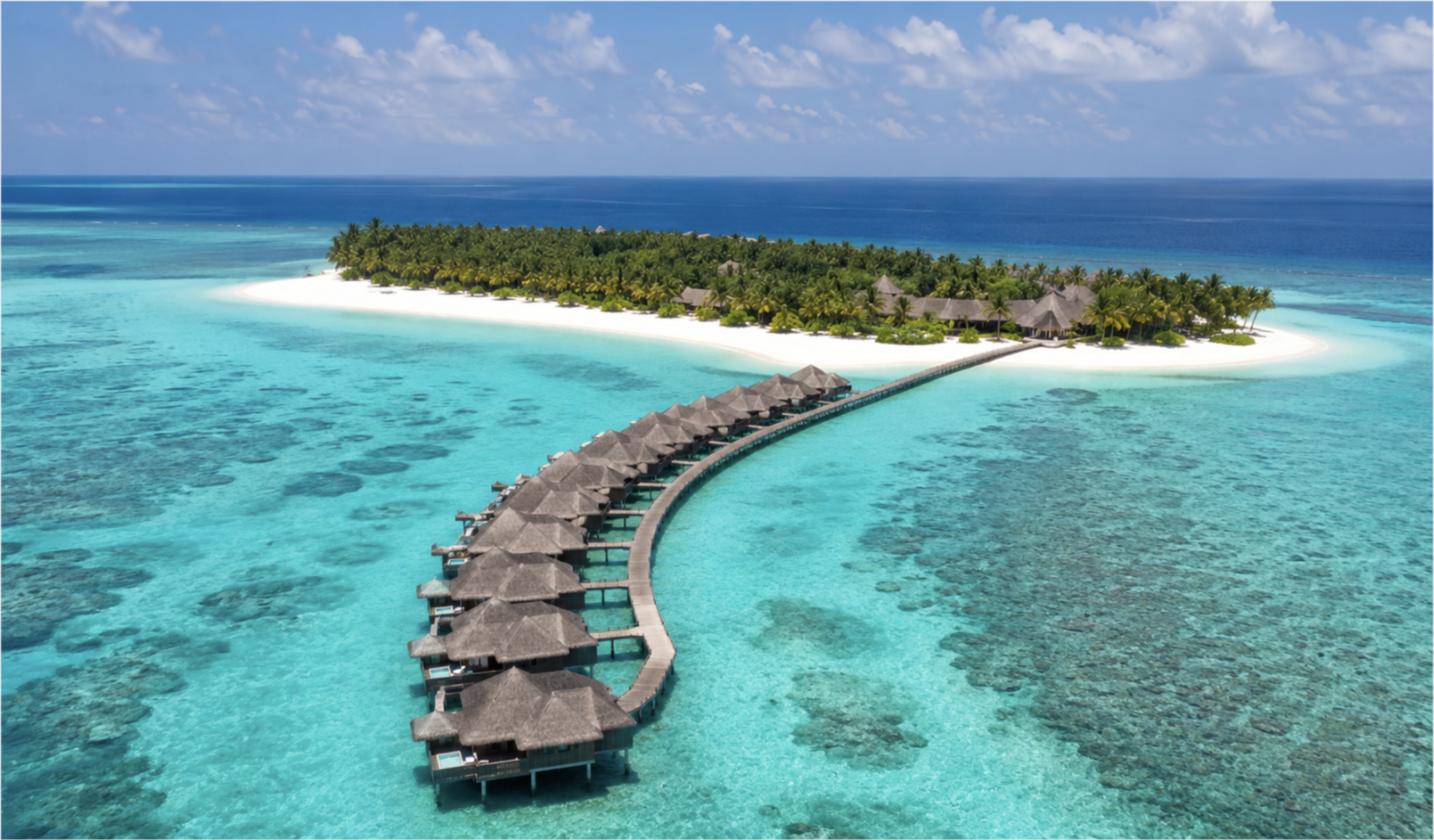 Aerial view of a Maldives resort with a curving row of thatched overwater villas beside a palm-covered island and turquoise reefest Resorts in Maldives: How to Choose the Right One