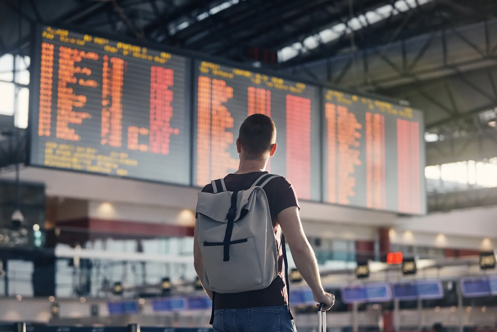 Traveller with a backpack checking connecting flights on an airport departure board