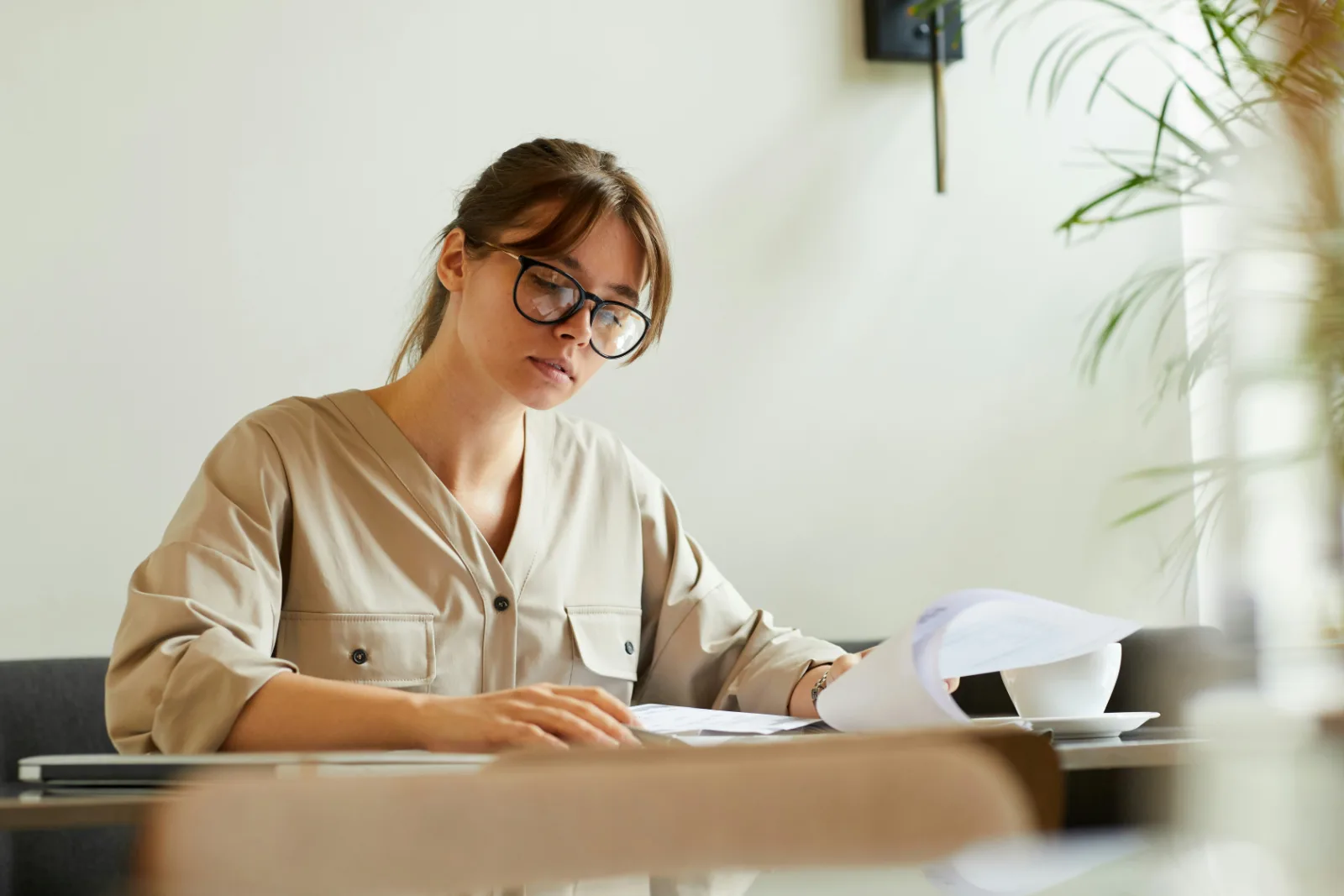 Woman reading through printed policy documents at a desk before buying travel insurance