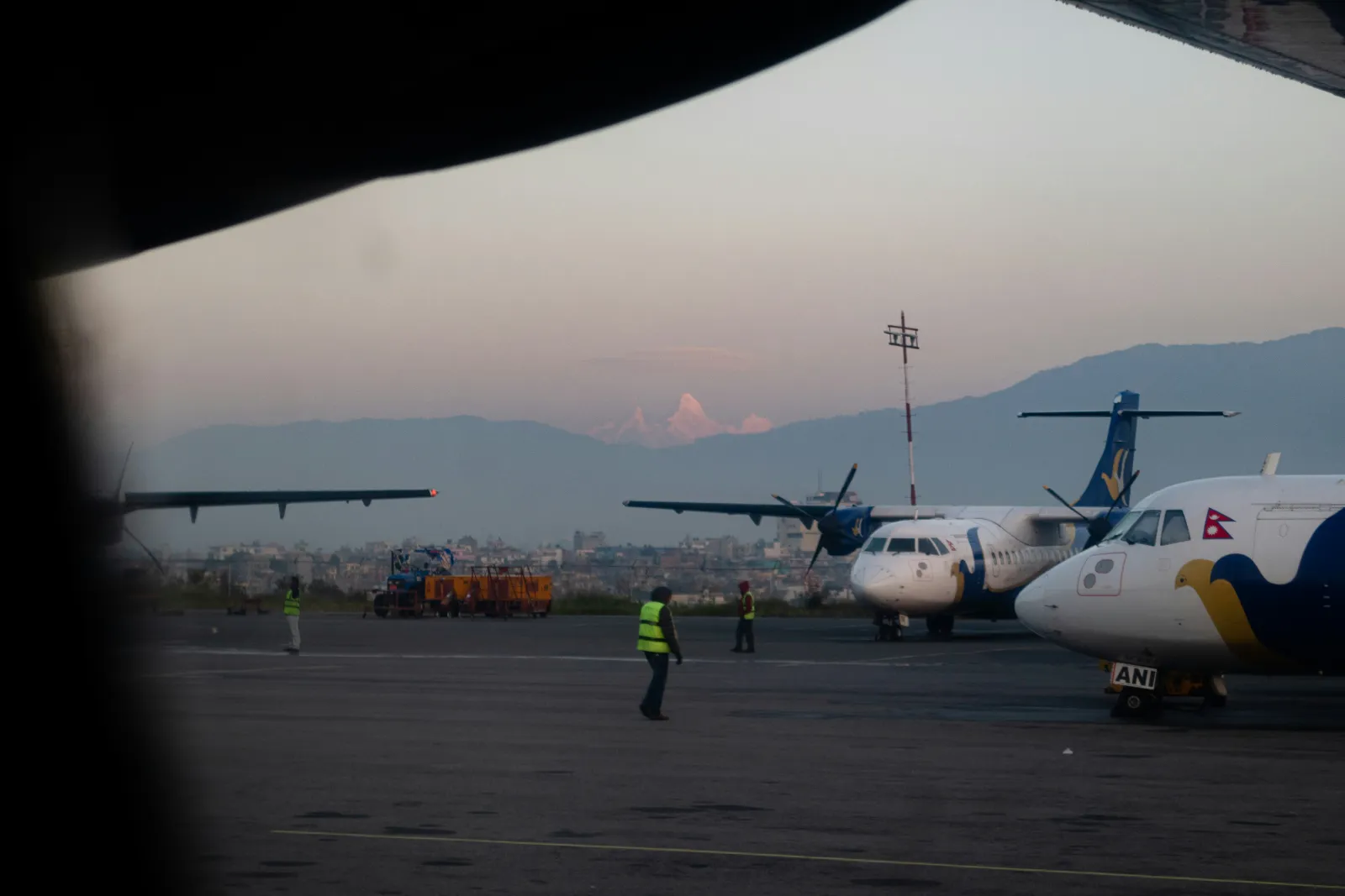 Aircraft parked at Tribhuvan International Airport in Kathmandu with hills rising behind the apron