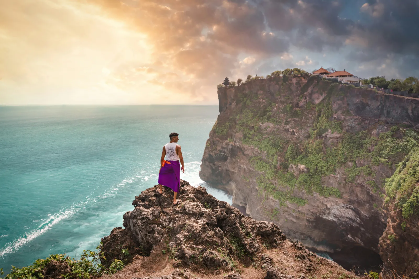 Traveller standing on the limestone cliffs at Uluwatu Temple above the Indian Ocean in Bali