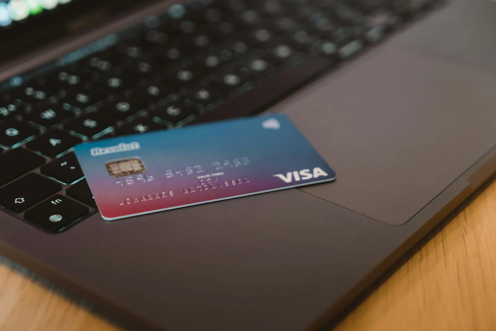 Visa bank card resting on a laptop keyboard, ready for card payments while travelling