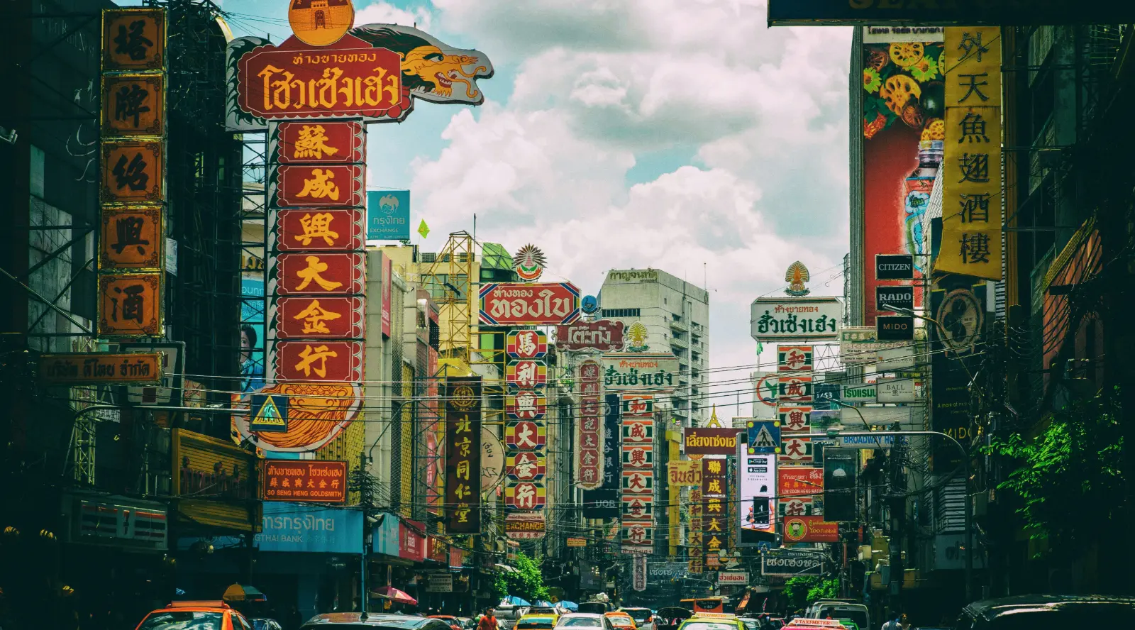 Yaowarat Road in Bangkok Chinatown with tall shop signboards and traffic by day