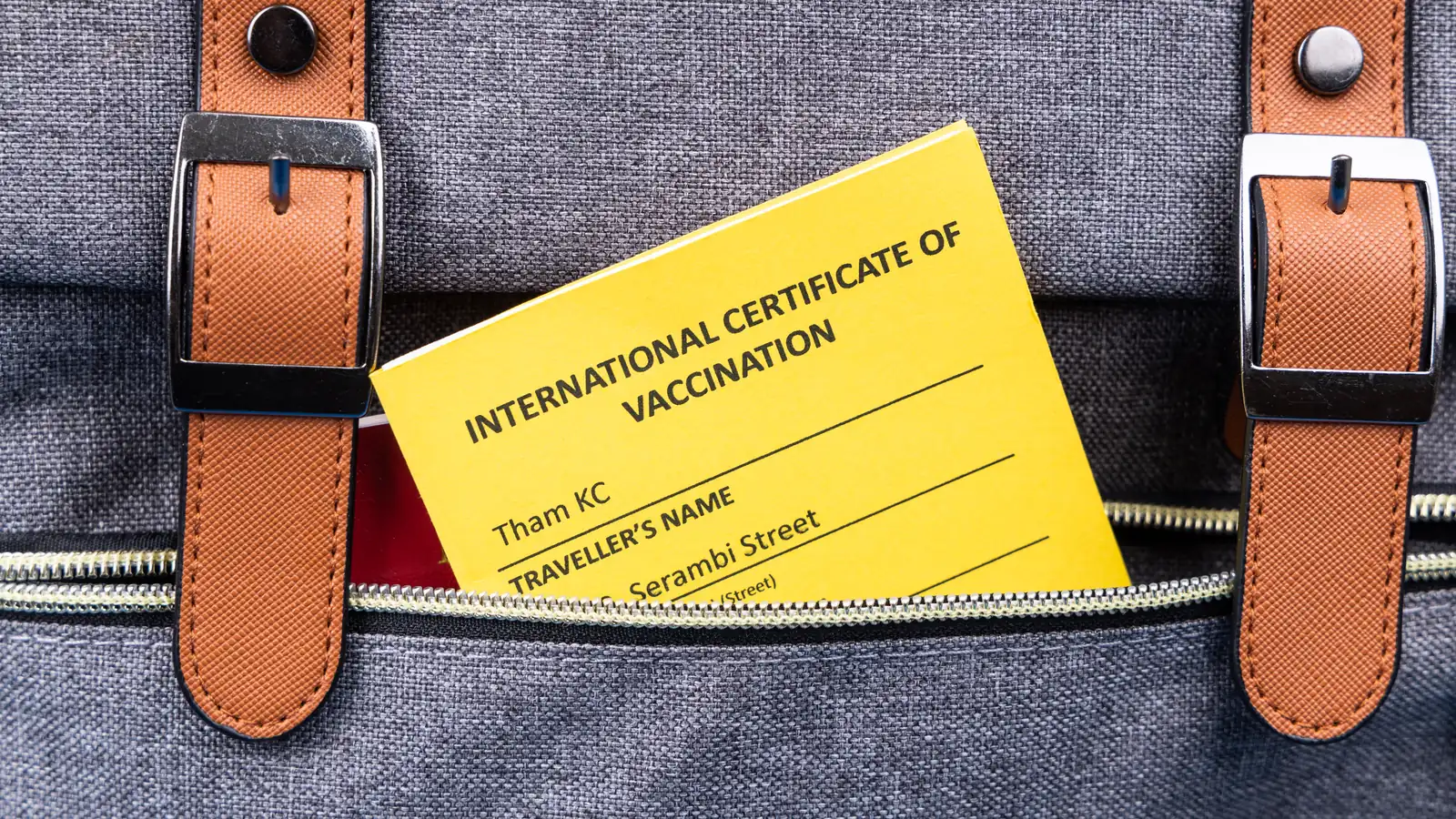 Yellow International Certificate of Vaccination tucked into the front pocket of a travel backpack