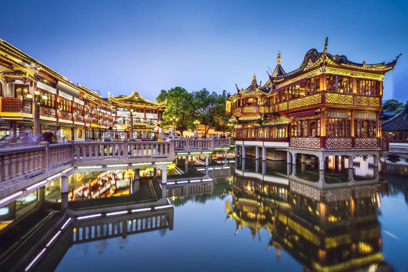 Traditional Yuyuan Bazaar pavilions lit at dusk and reflected in the pond beside Yu Garden in Shanghai